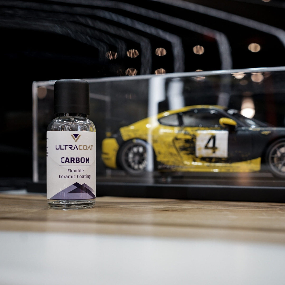 ULTRACOAT Carbon bottle displayed in front of a model car